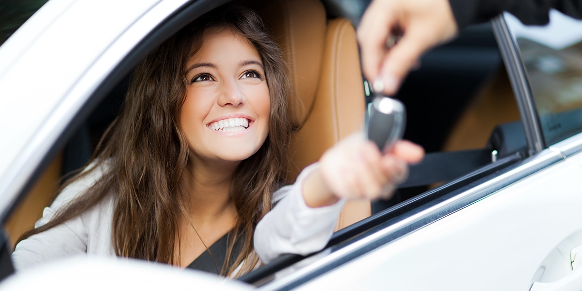Happy woman in car receiving her car keys.