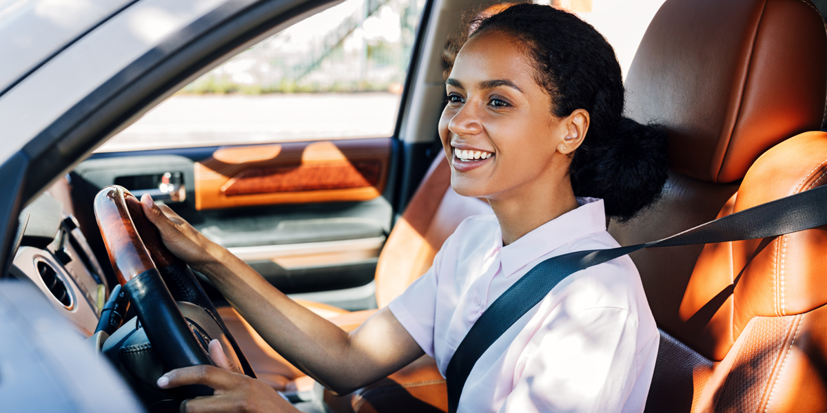 Happy woman holding a steering wheel in the vehicle